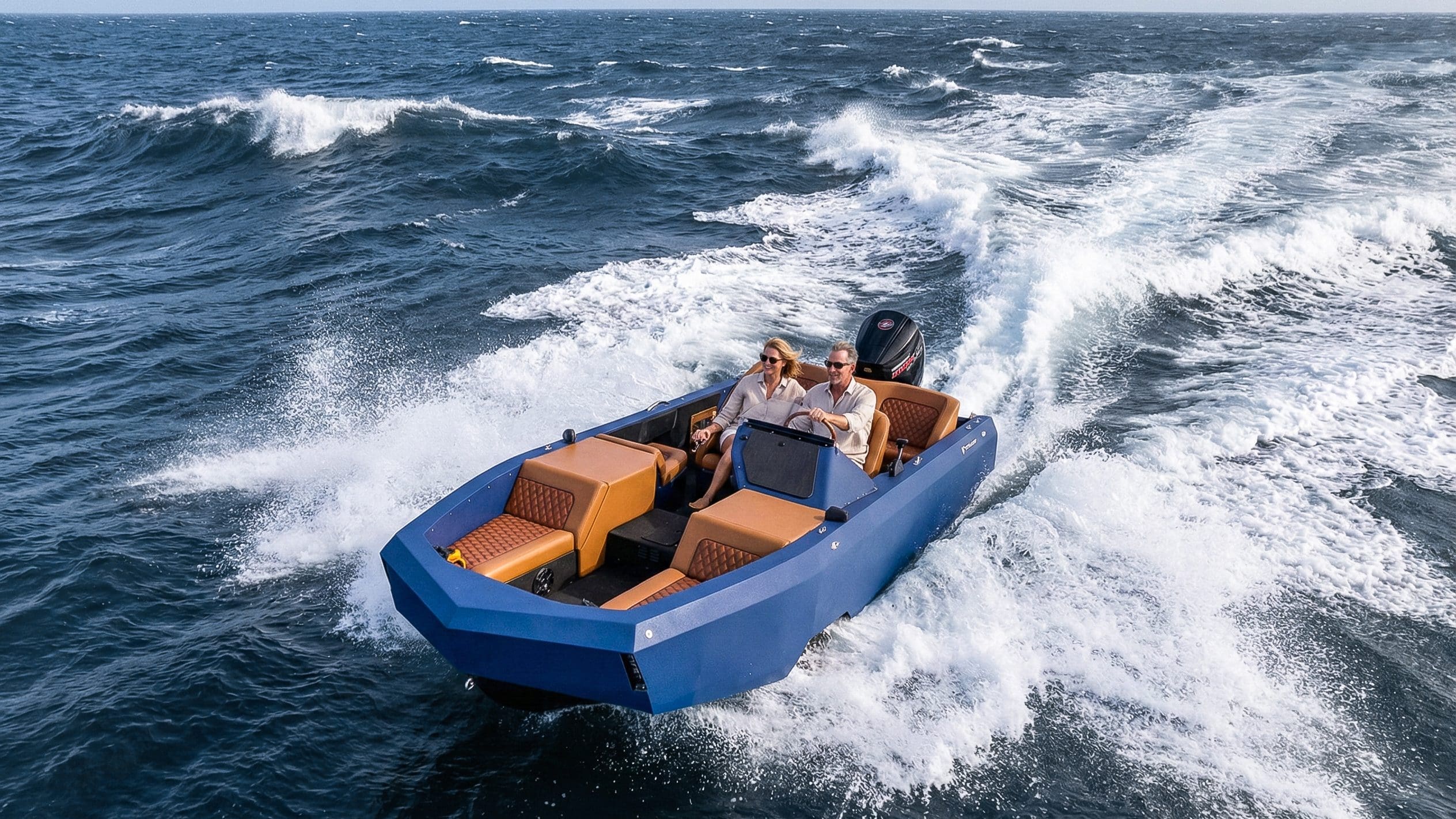 An aerial view of a couple in a dark blue motorboat at ocean waves